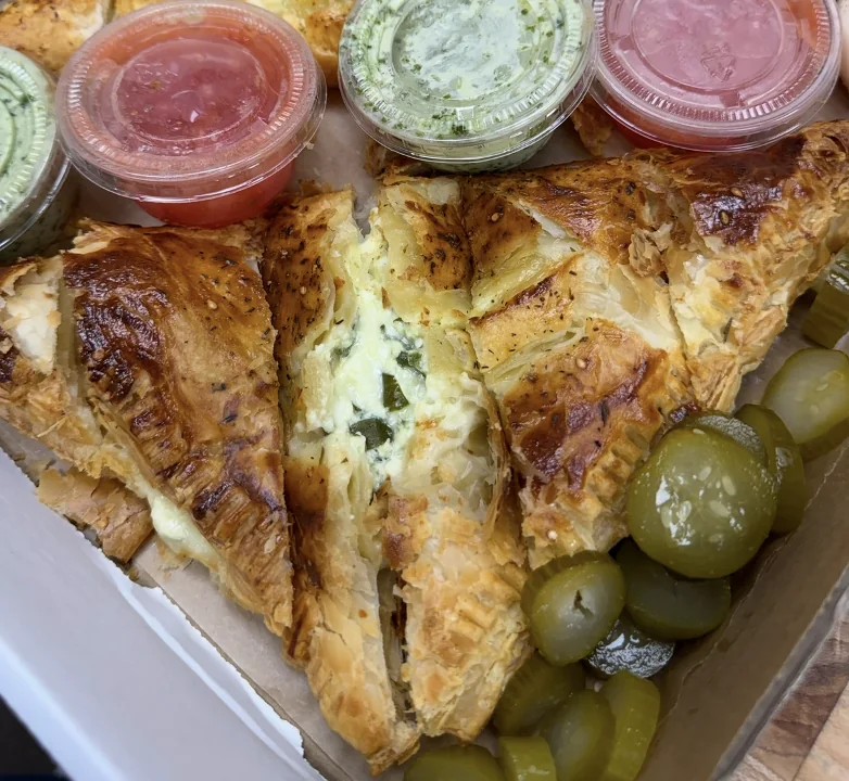 Spinach and cheese burekas cut open beside olives and dips