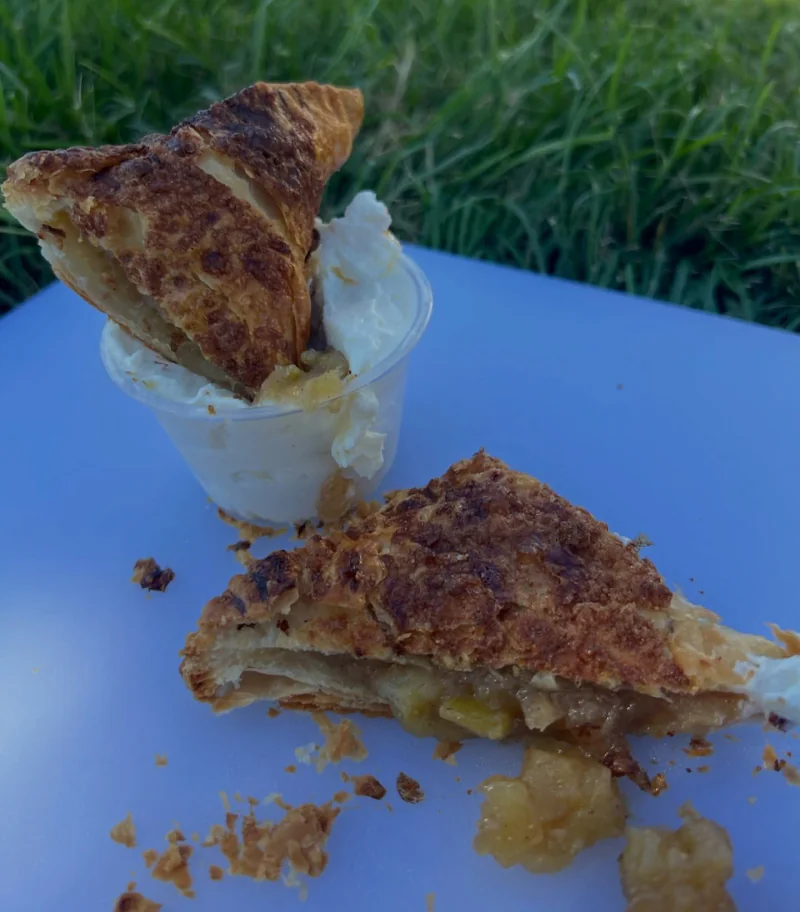 Apple pie bureka cut open beside a honey ricotta dip on a blue outdoor table