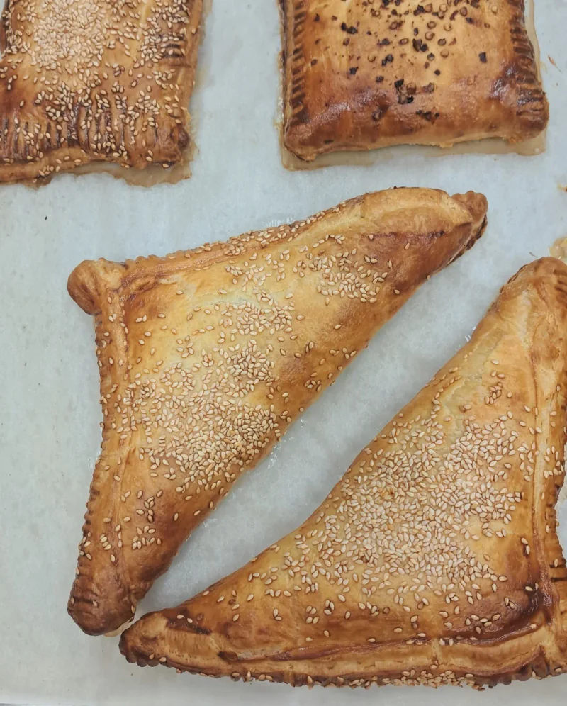Freshly baked triangular and rectangular burekas on parchment
